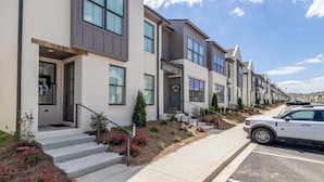 A row of modern townhouses with a front porch, a driveway, and a parked car. - Hemingway Haven (Oxford)