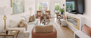 A modern living room with a sofa, armchairs, a coffee table, a TV, and a fireplace.