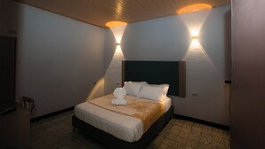 A hotel room with a bed, bedside lamps, a headboard, a chair, and a door. - Casa Santa Cruz | Private Jacuzzi | 6 Suites | 16+ (Cartagena de Indias)