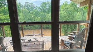 Ein Zimmer mit großem Fenster und Blick auf eine Holzterrasse mit Gartenmöbeln.