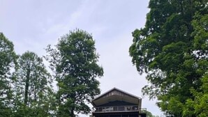 Ein Gebäude mit einem geneigten Dach, umgeben von Bäumen und Gras.