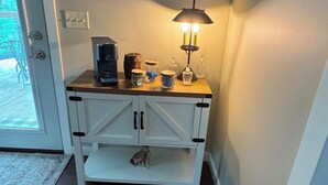 Eine Küchenzeile mit einer Kaffeemaschine, einer Lampe und einer Katze auf einem Regal.