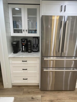 Eine Küche mit einem Edelstahlkühlschrank, einer Kaffeemaschine und einem Mixer auf der Arbeitsfläche.