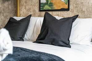 A bed with white and black pillows, a dark blanket, and a painting on the wall. - Deluxe pad– Bham Centre, Pool Table, Next to Canal +Netflix (Birmingham)