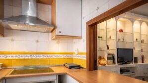 Keittiössä on moderni liesi, sisäänrakennettu uuni ja mikroaaltouuni. Työtaso on puuta ja seinässä on keltainen välitila.