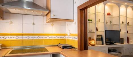 A kitchen with a modern stove, a built-in oven, and a microwave. There is a wooden countertop and a yellow backsplash.