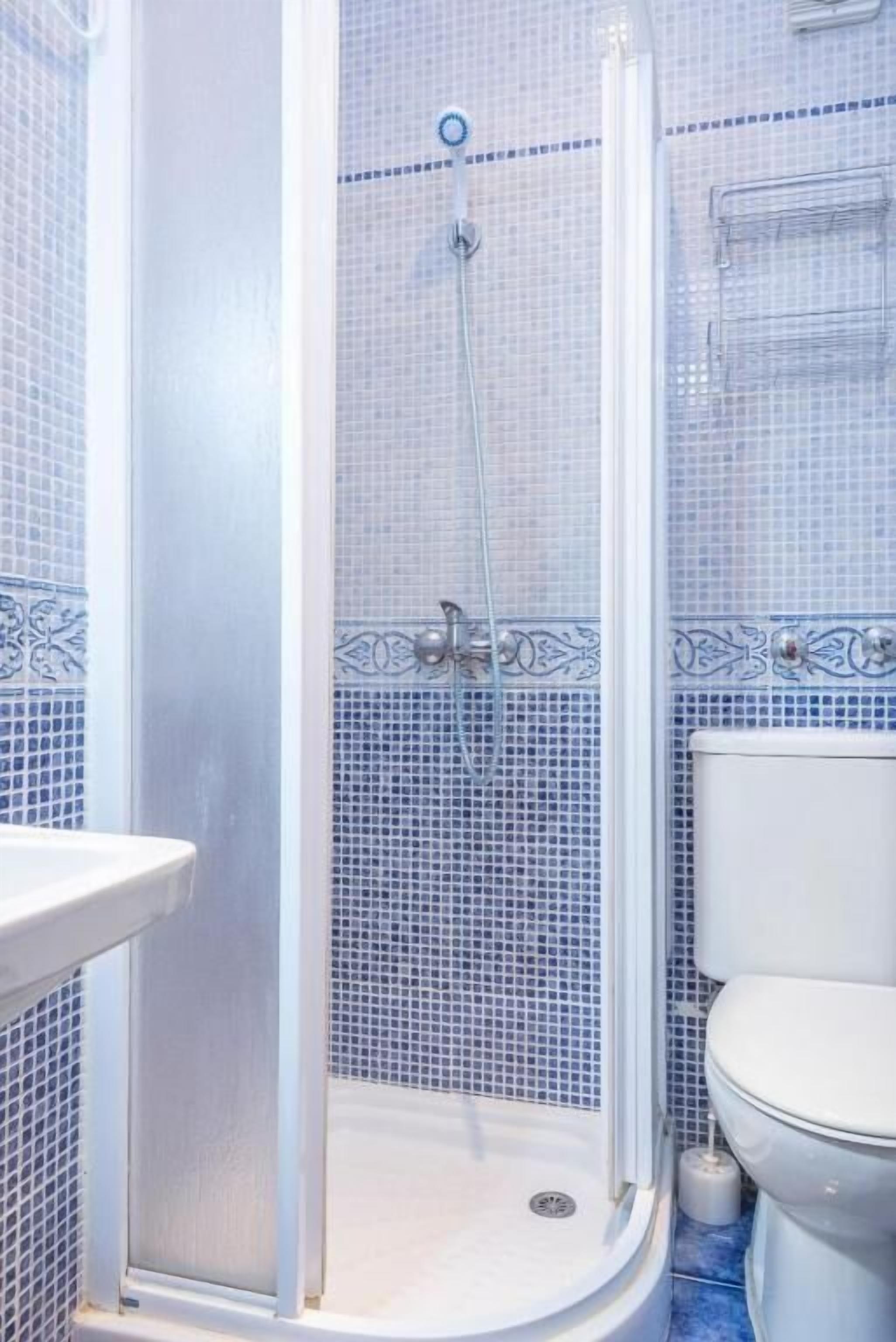 Een badkamer met douche, toilet en wastafel.