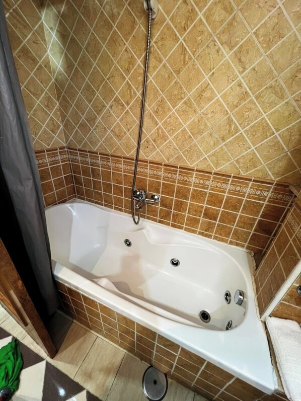 A bathroom with a bathtub, shower, and tiled walls.