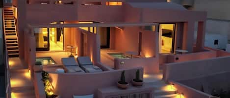 A modern multi-story building with outdoor seating areas, a pool, and a staircase.