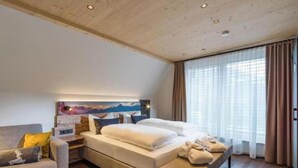 Et soveværelse med seng, sofa, et natbord og et billede på væggen.