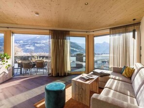 A spacious living area with a sofa, coffee table, and a view of mountains through large windows. - Luxurious spa apartments for relaxing vacations in Tyrol (Zellbergeben)