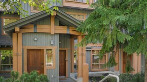 A modern building with a wooden facade, a front door, and a small porch area. - Bluffs - Luxury 2 Bed Ski in Ski out - Views! (Whistler)