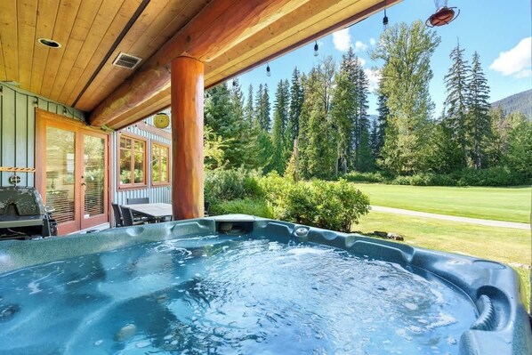 Ein Whirlpool mit einer Holzterrasse und Blick auf einen Wald.