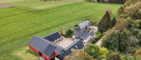 Een landgoed in het buitengebied met meerdere gebouwen, een groot groen veld en uitzicht op zee.