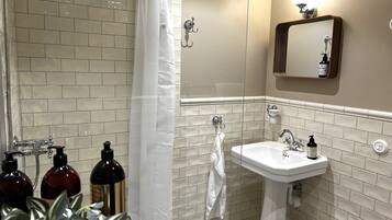 A bathroom with a shower, sink, and mirror.