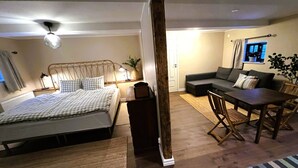 Een slaapkamer met een bed, nachtkastje, lamp en een raam met gordijnen.