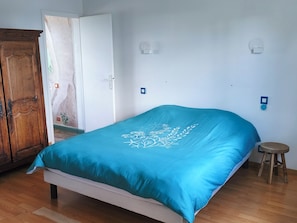 Une chambre à coucher avec un lit, une armoire en bois et une porte donnant sur une autre pièce.