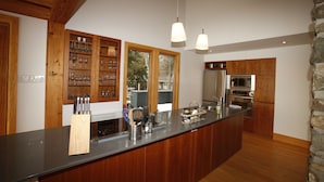 Una cocina moderna con armarios de madera, una isla grande, electrodomésticos de acero inoxidable e iluminación colgante.