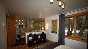 Un dormitorio con una cama grande, un tocador con espejo, una ventana con cortinas y suelo de madera.