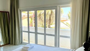 Una habitación de hotel con una cama grande, vistas al exterior y una ventana con cortinas.