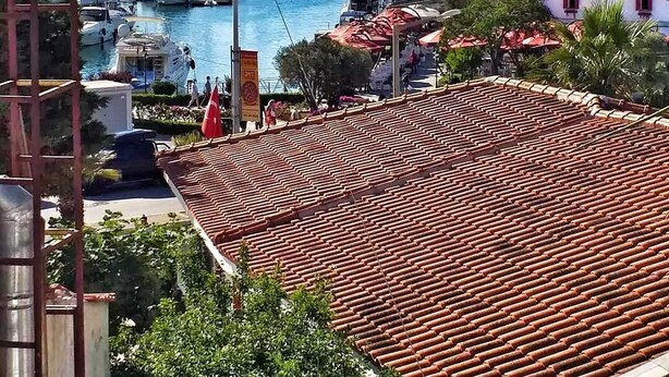 Un puerto deportivo con barcos, cielo despejado y montañas al fondo.