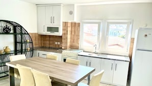 Una cocina compacta con mesa, sillas, estufa y refrigerador.