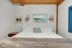 Un dormitorio con cama, dos lámparas de pared, un cuadro y una mesita de noche.