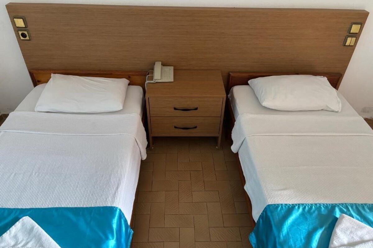 Ein Doppelzimmer mit zwei Betten, jeweils mit Kissen und einem Nachttisch mit Telefon.