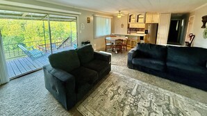 A spacious living area with a large sofa, a dining table with chairs, and a kitchen area with cabinets and a refrigerator.