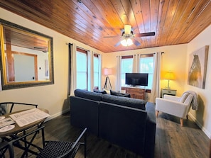 A cozy living room with a sofa, television, and a ceiling fan. - Willow Whisper Cottage (Hot Springs)