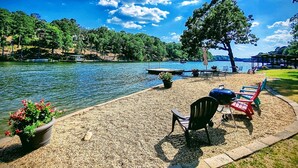 A lakeside deck with outdoor seating, a grill, and a view of the lake and surrounding trees. - Wildflower's Escape (Hot Springs)