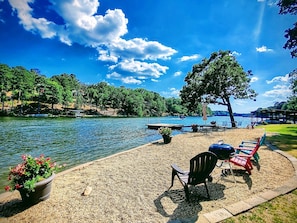 A lakeside deck with outdoor seating, a grill, and a view of the lake and surrounding trees. - Wildflower's Escape (Hot Springs)