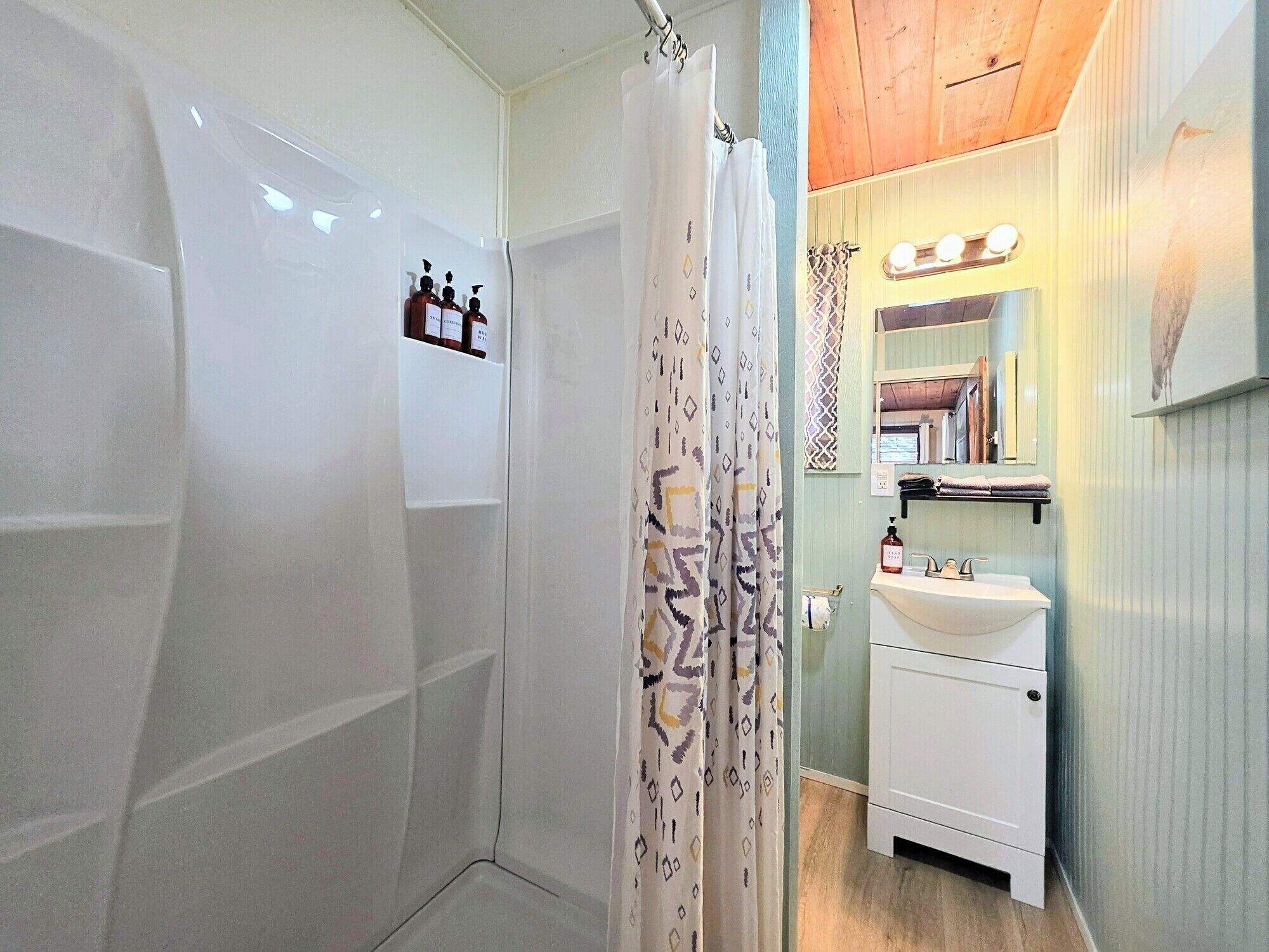 Ein Badezimmer mit Dusche, Waschbecken und Spiegel.