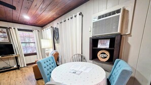 Habitación acogedora con una mesa redonda, dos sillas, un televisor y un cartel que prohíbe fumar, vapear y el consumo de marihuana.