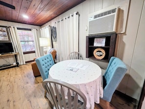 A cozy room with a round table, two chairs, a television, and a sign prohibiting smoking, vaping, and marijuana use. - Heron's Nest Cottage (Hot Springs)