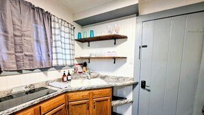 A kitchen with wooden cabinets, a granite countertop, a sink, and a door with a handle. - Pebble Beach Cottage (Hot Springs)
