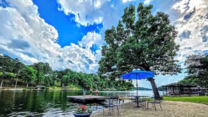 A lakeside park with a dock, picnic tables, and a blue umbrella. - Pebble Beach Cottage (Hot Springs)