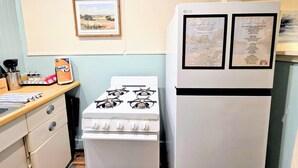 A kitchen with a white stove, a refrigerator with a menu, and a framed picture on the wall. - Serenity Shores Cottage (Hot Springs)