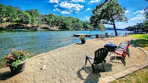 Una terrazza sul lago con posti a sedere all'aperto, un barbecue e vista sul lago e sugli alberi circostanti.