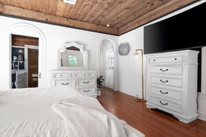 A bedroom with a large bed, white dresser, and a mirror. - Venue 1925 with pool (Belton)