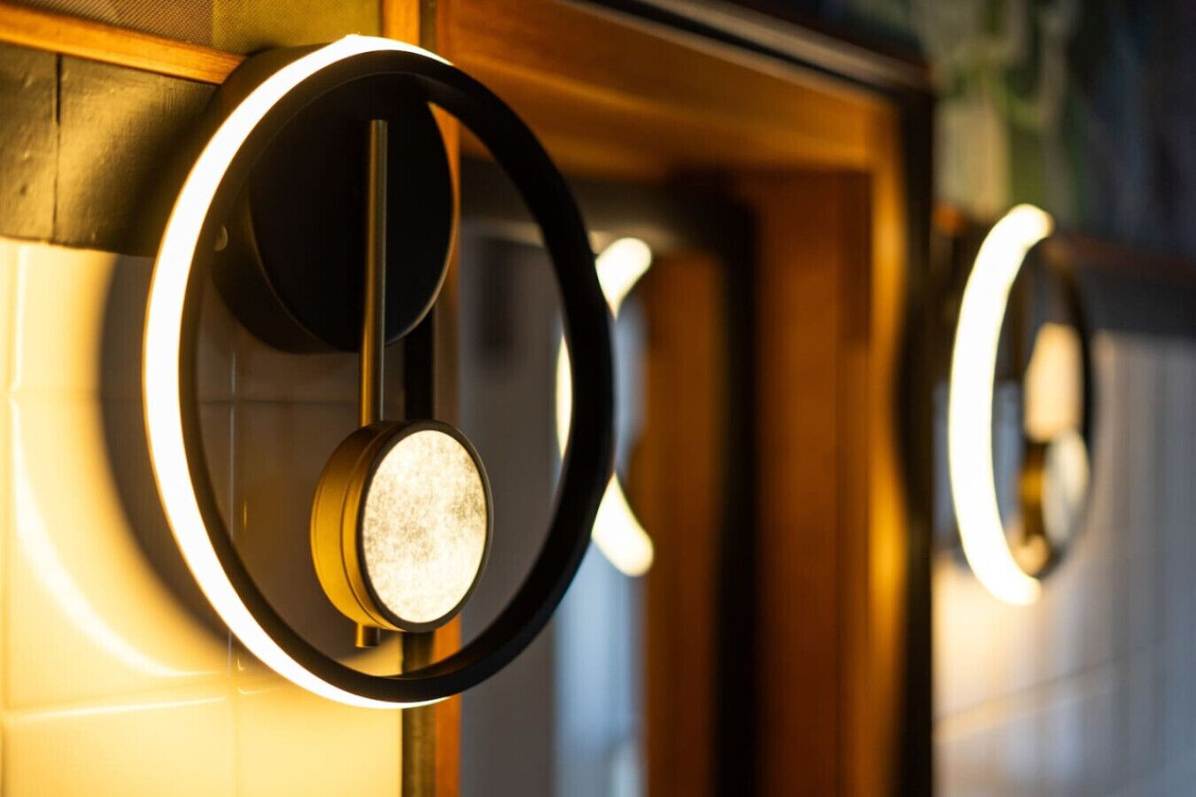 A series of circular light fixtures with a central round element, mounted on a wall with a wooden frame.