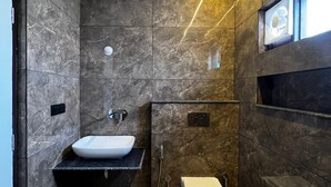 Un baño moderno con lavamanos de mármol, inodoro y ducha.