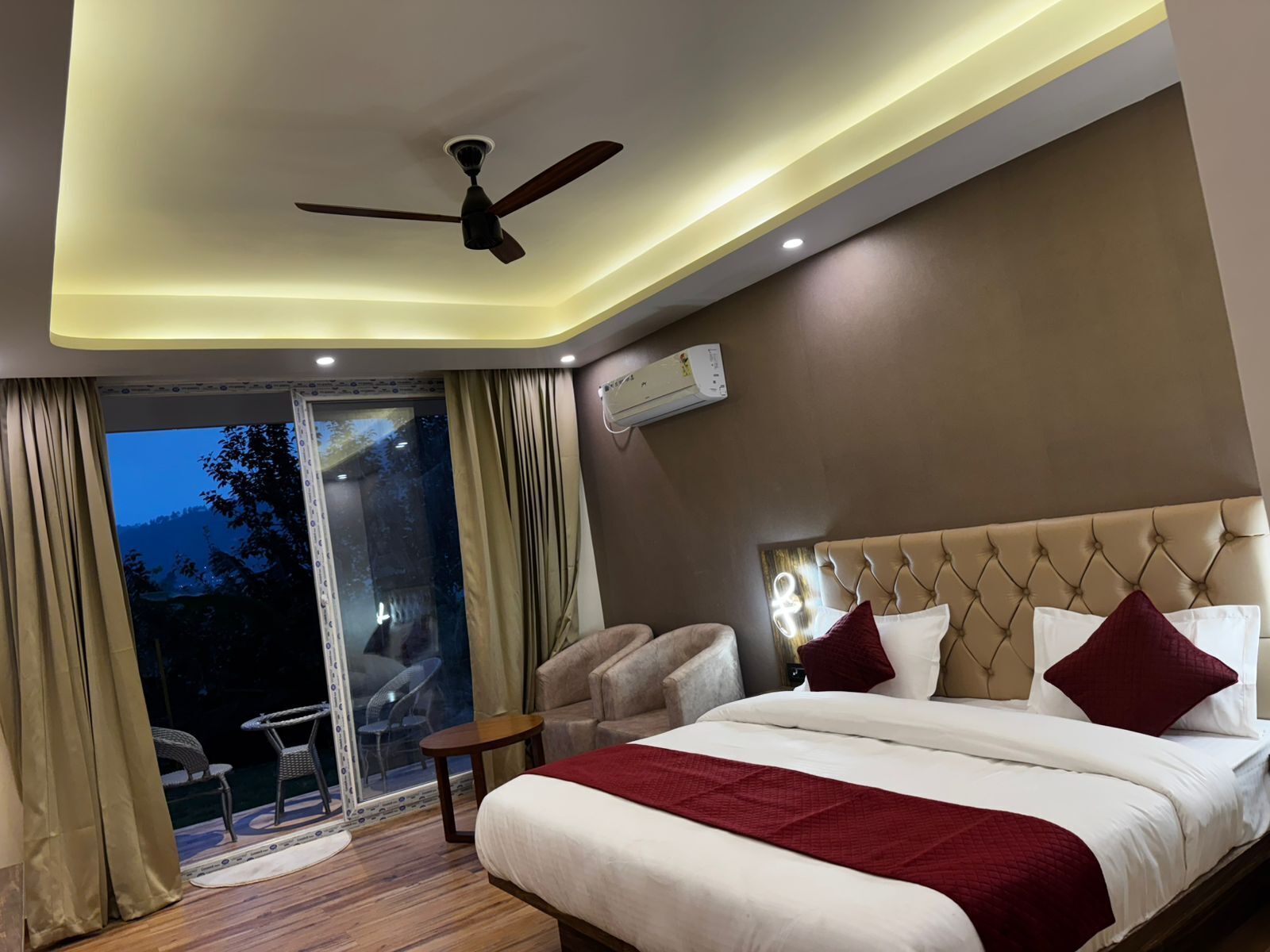 A bedroom with a bed, a ceiling fan, a window with curtains, and an air conditioning unit.