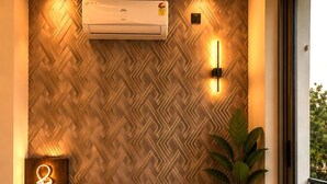 Un interior moderno con una pared con motivo de espiga, un sofá, una mesita con una vela y un equipo de aire acondicionado.