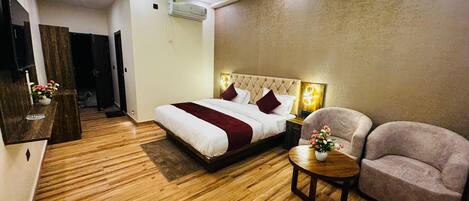 Une chambre d’hôtel équipée d’un lit, d’une chaise, d’une petite table, d’un ventilateur de plafond et d’un appareil de climatisation.