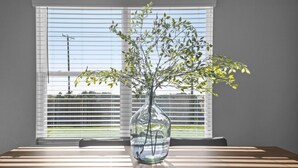A clear view of a room with a table, a vase with a plant, and a window with blinds. - Brand-New Med District Home (Temple)