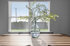 Ein klarer Blick in einen Raum mit einem Tisch, einer Vase mit Pflanze und einem Fenster mit Jalousien.