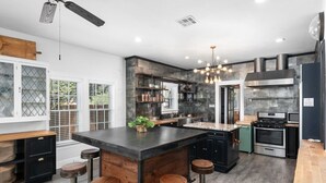 A modern kitchen with a central island, bar stools, a built-in oven, and a stainless steel range hood. - Venue 1925 with pool (Belton)
