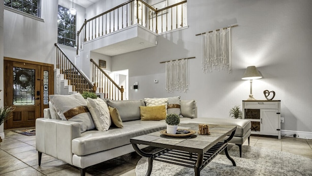 A spacious living room with a high ceiling, a staircase, a sofa set, a coffee table, and a lamp. - Triple C Retreat + Pool & Spa (Temple)