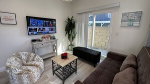 A living room with a sofa, a bean bag chair, a small table, a TV, and a potted plant. - Huntington Beach 2bed/2bath house.| Near Beach, Dining, Family Fun & Relaxation (Huntington Beach)